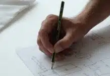 person holding black pencil on white printer paper