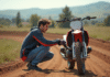 Jeune homme en motocross examinant sa moto en pleine nature